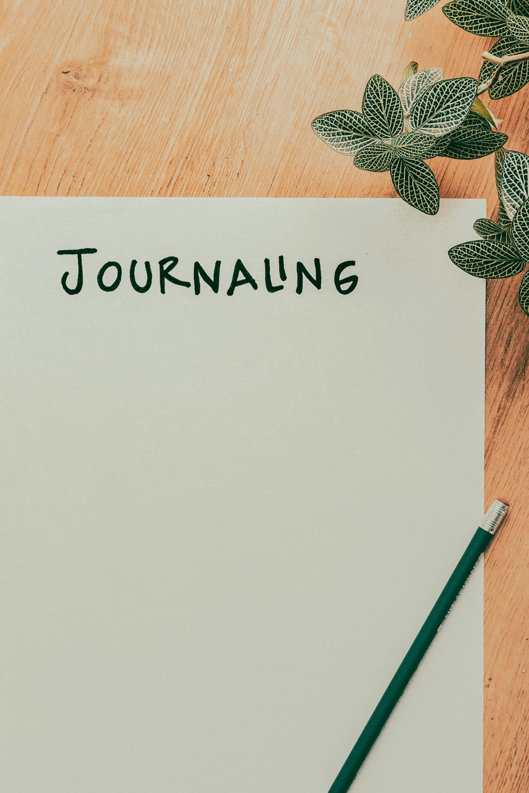 A blank note pad on a desk with the word 'journaling' written at the top.